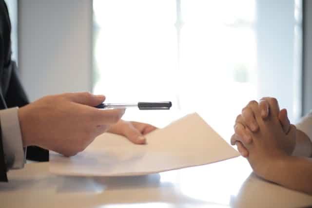 The hands of a lawyer and client with documents from an accident.