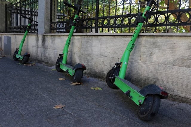 E-scooter available for rental next to a fence.