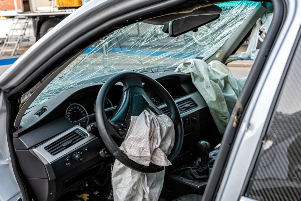 Broken car glass and deployed airbags after an accident.