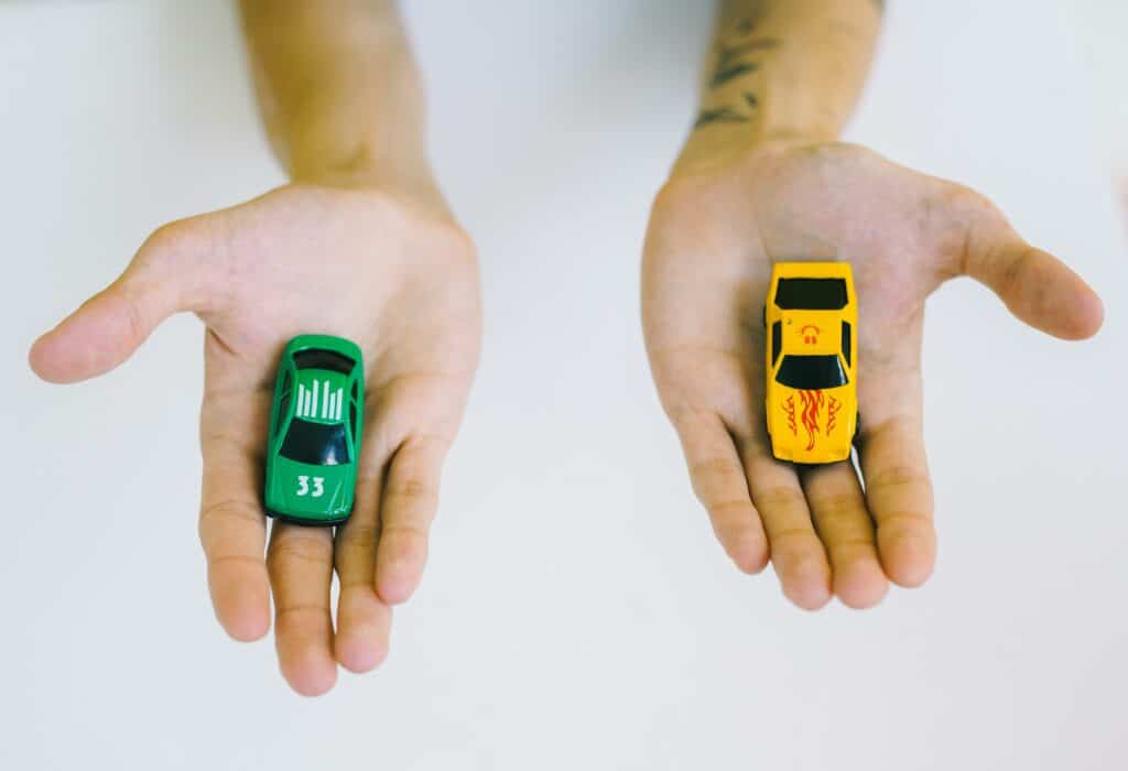 Dos coches de juguete en la palma de cada mano.