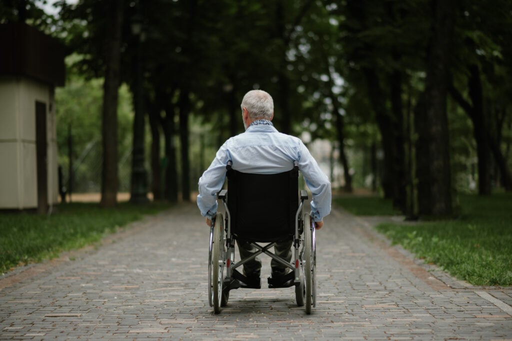 Senior in a wheelchair outside a nursing home.