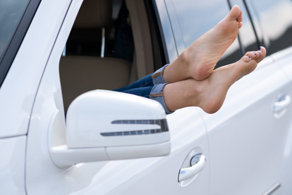 person with their bare feet hanging out of a car window