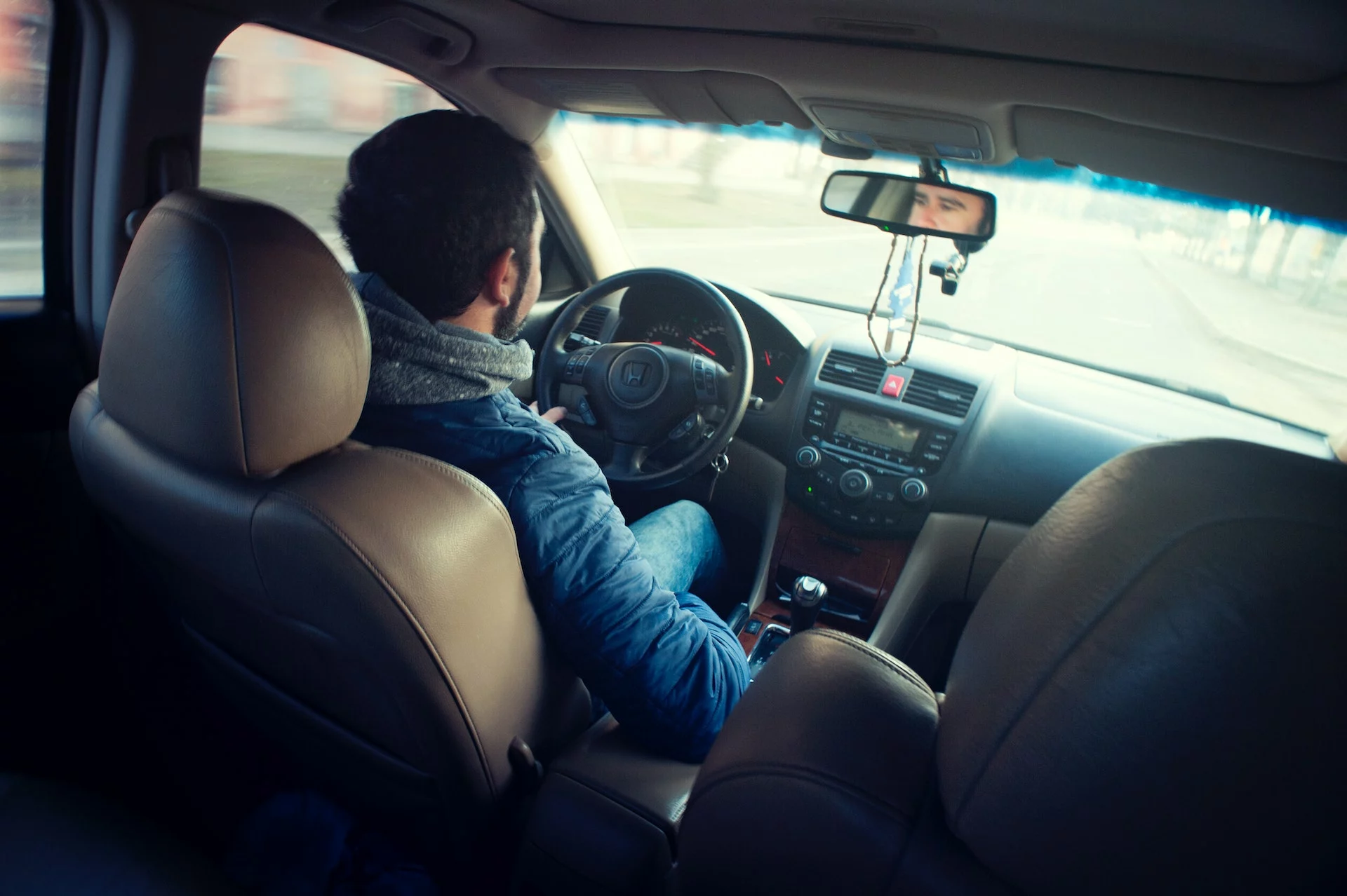an Uber driver wearing a blue jacket inside the car