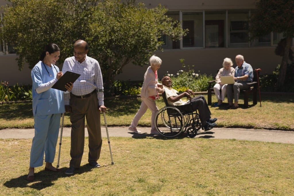 Front view of senior people and female doctor in garden on a sunny day