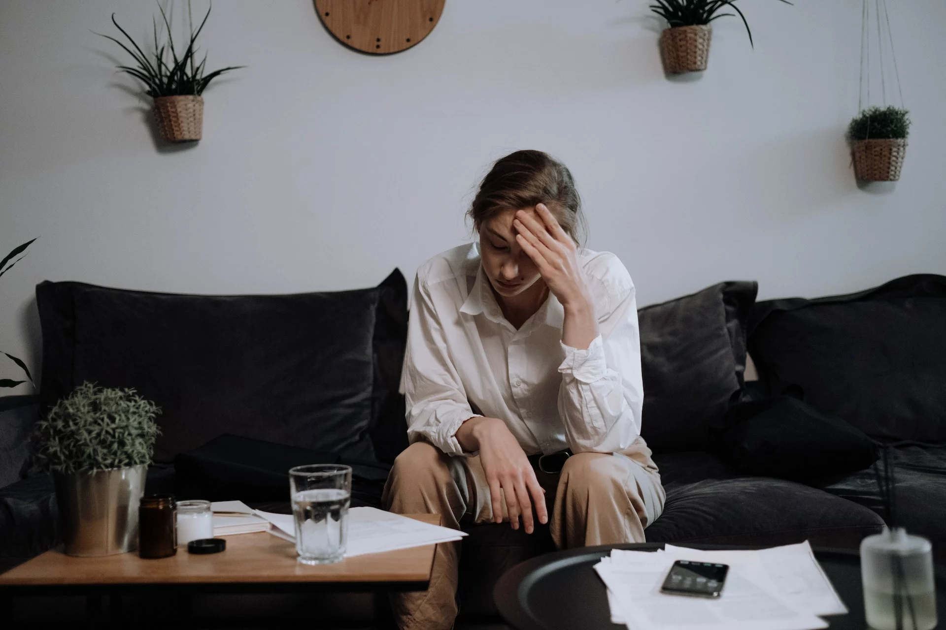 Woman sitting on her sofa clutching her forehead