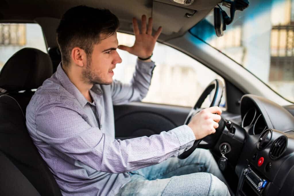 Side view of an angry man driving a car with road rage 