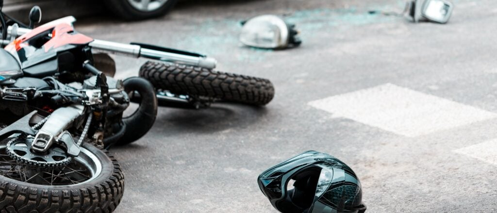 A motorcycle lies on the ground after an accident with a car.