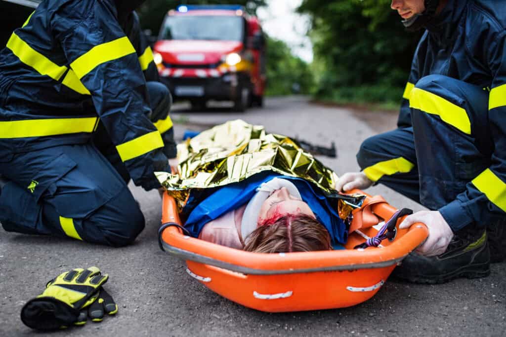 Mujer atropellada es levantada por los paramédicos a la ambulancia.