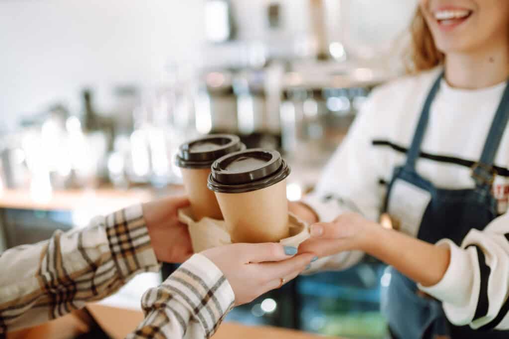 Barista at a Starbucks coffee shop gives two coffees to a customer.