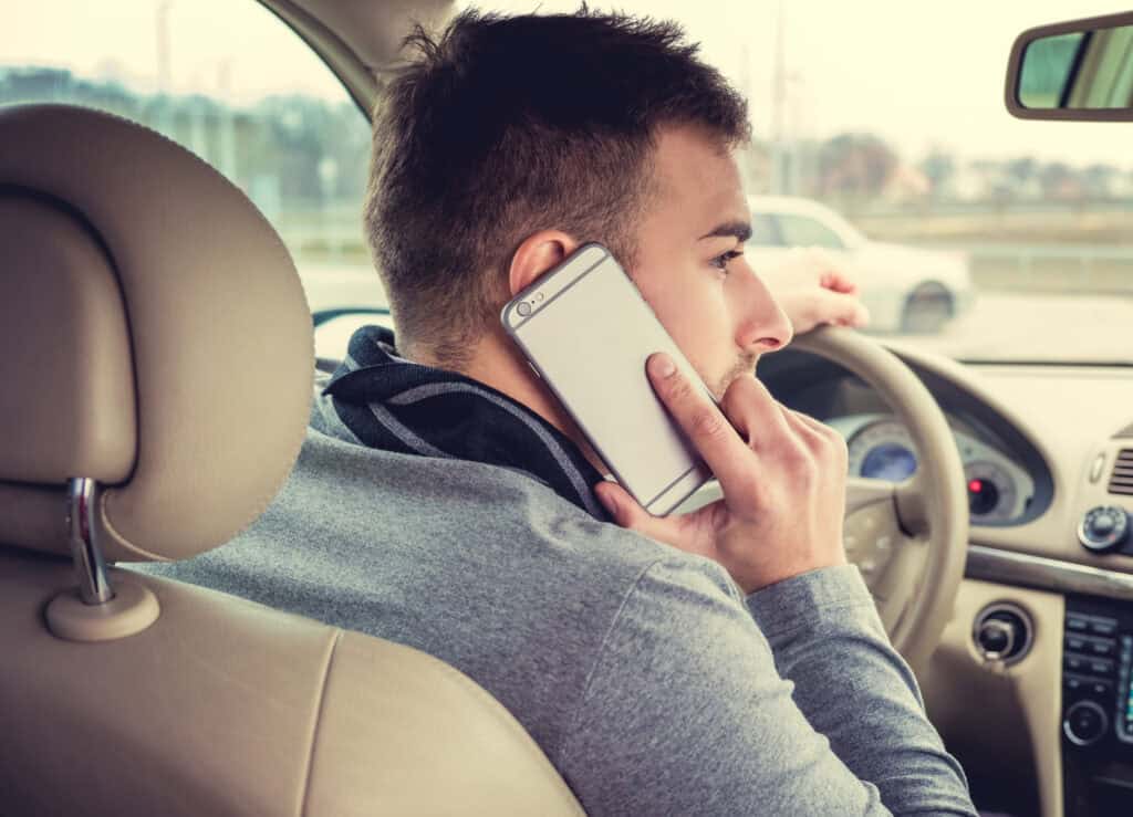 Man distracted driving while talking on his smartphone.