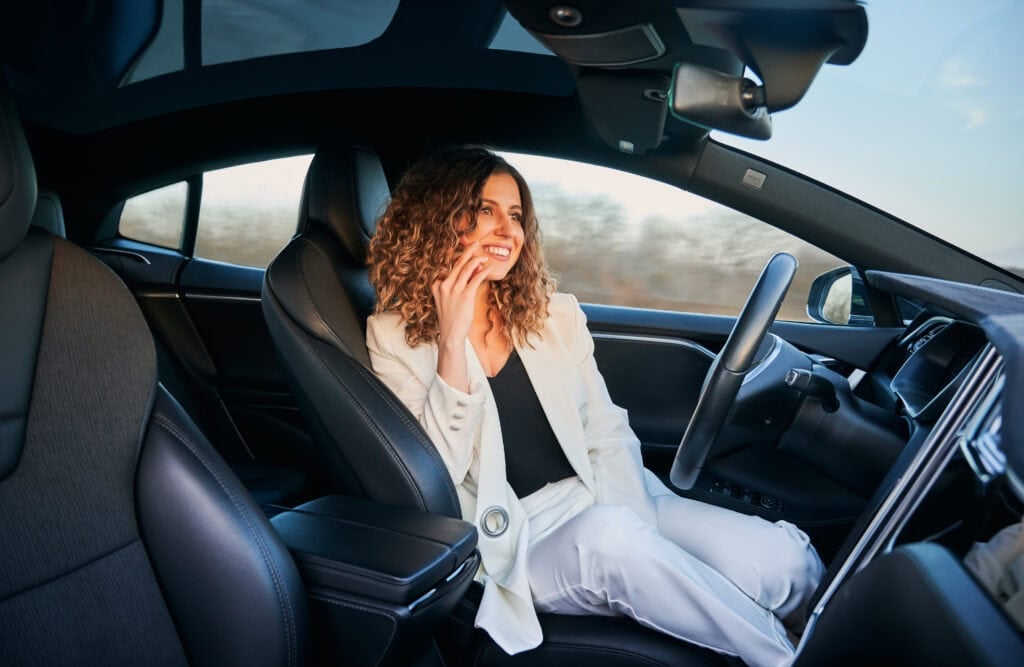 Picture of a woman sitting in the driver's seat of an autonomous vehicle using Tesla's Autopilot