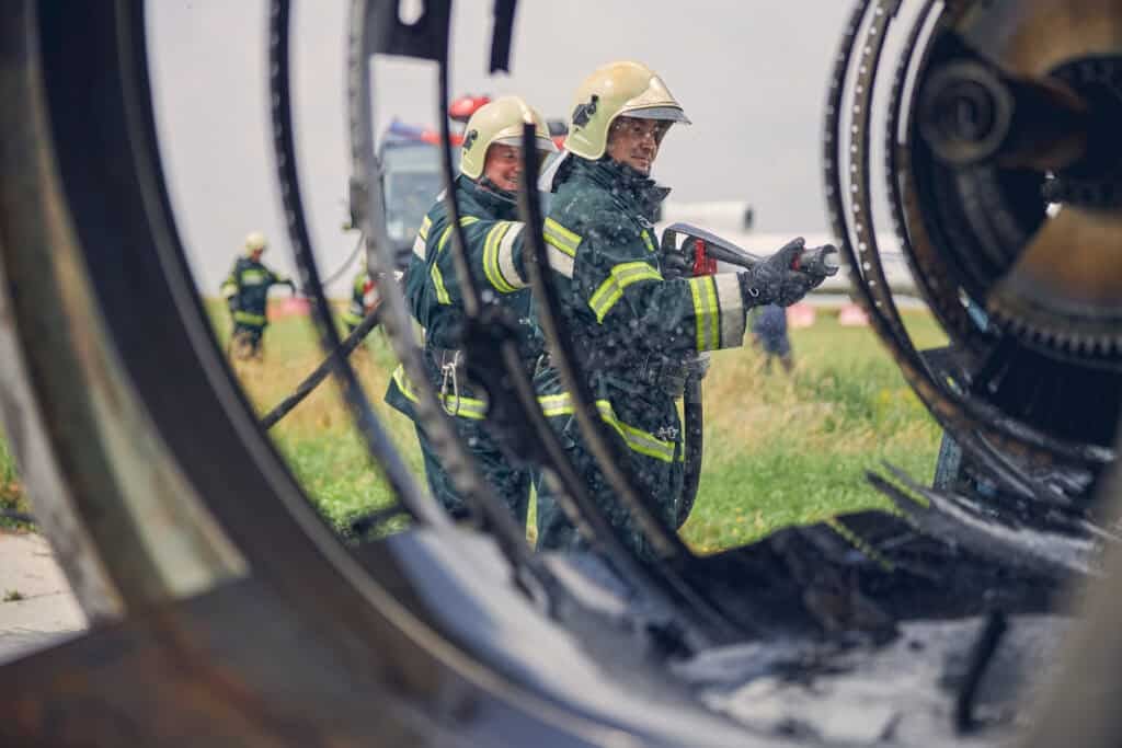 Firefighters extinguish new burst of fire from helicopter crash.