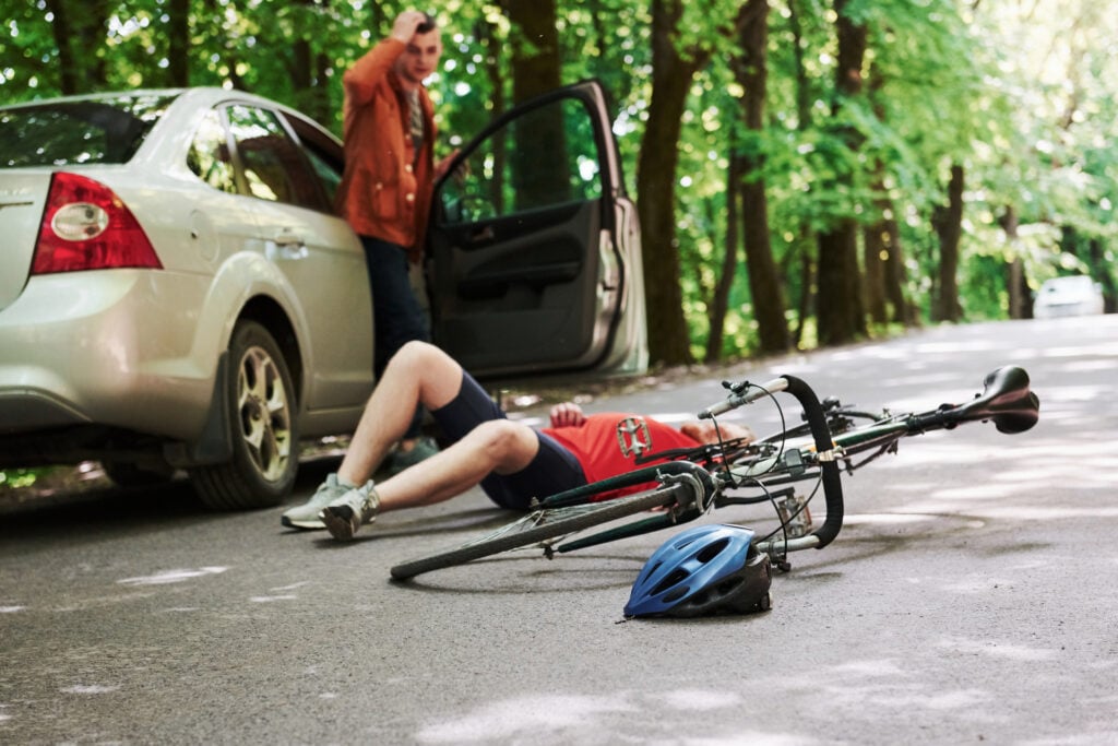 A car driver gets out of the car after crashing into a bicyclist.