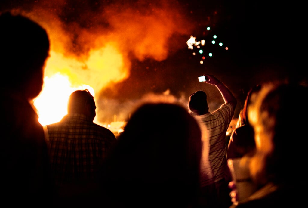 People watching fireworks with a wildfire in the background.