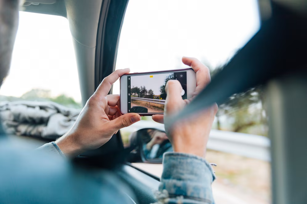 A person taking a photo of the road and surroundings from the passenger seat of a car