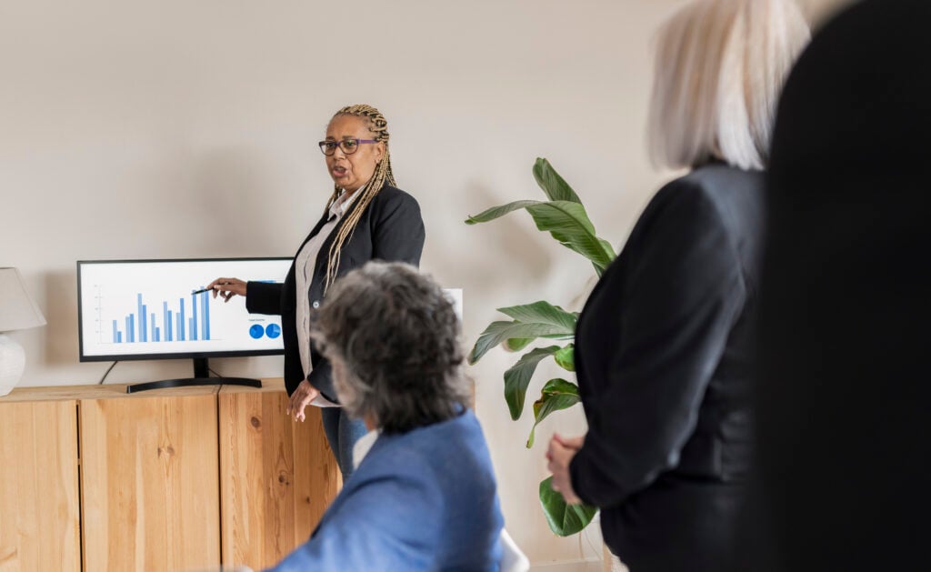 A businesswoman presents performance data to attentive colleagues in a modern corporate setting