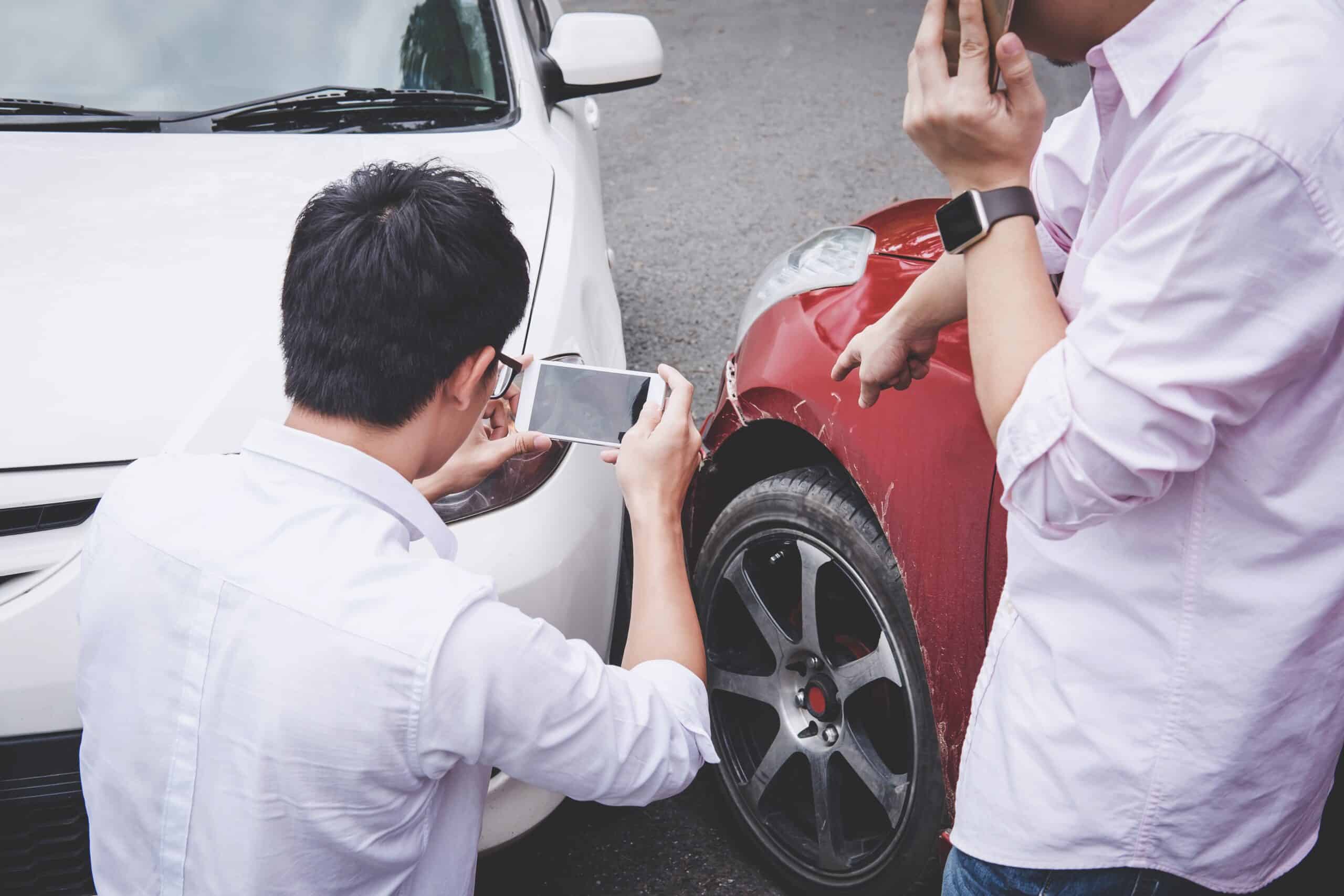 Two drivers arguing after a car accident and making a phone call to insurance.