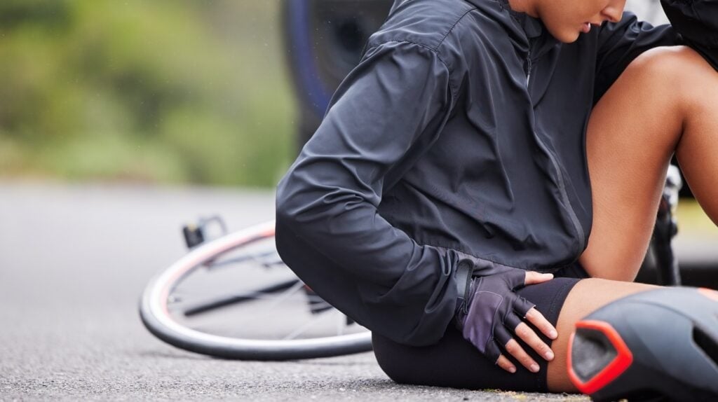 Woman injured in a bicycle accident, lying on the ground.