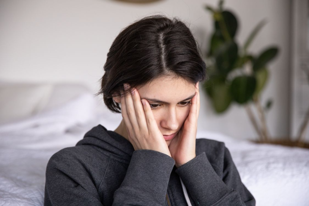 Mujer se sujeta la cabeza por lesiones traumáticas con gesto de dolor.